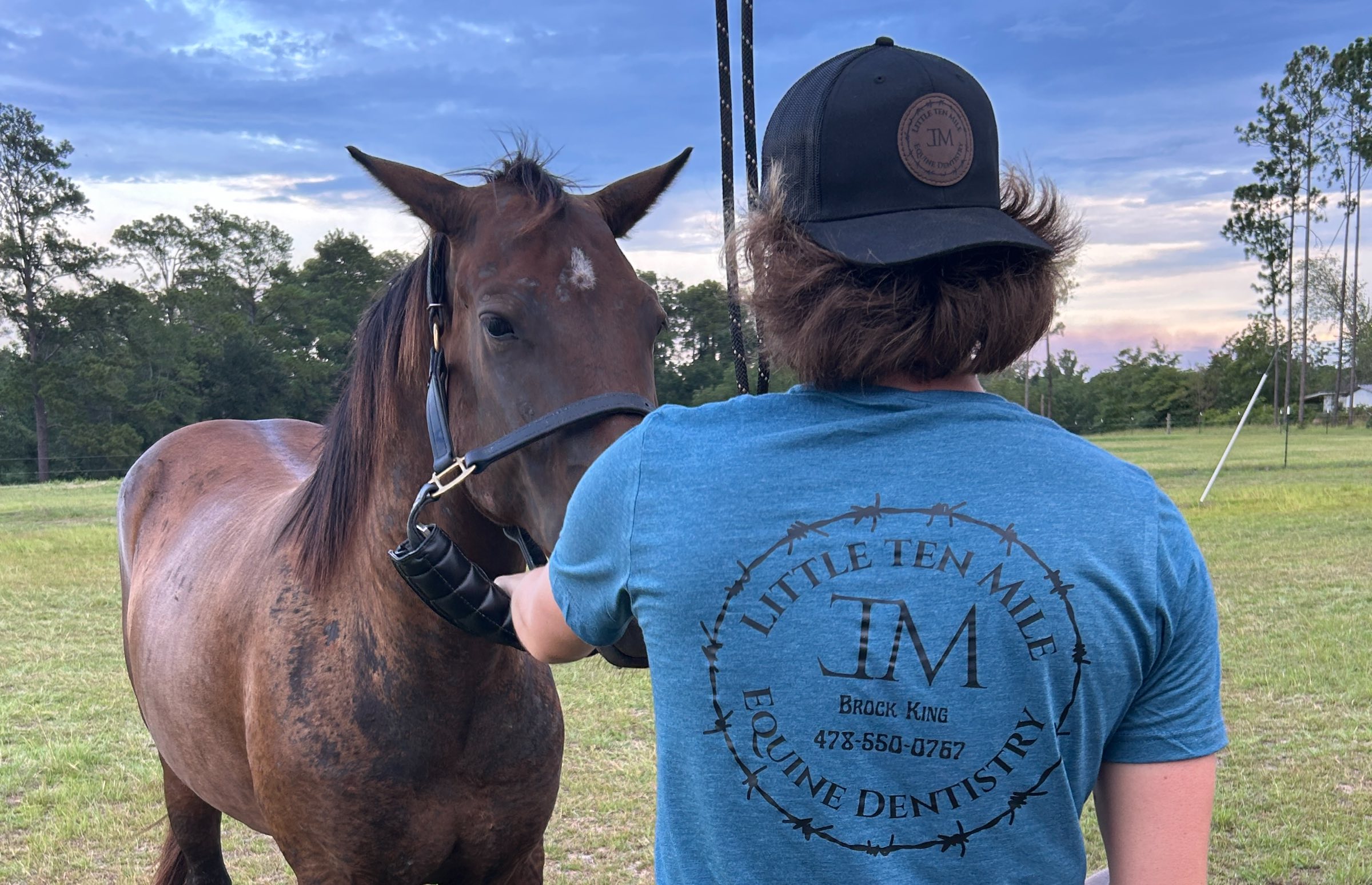 Brock King haltering a horse in a pasture at dusk